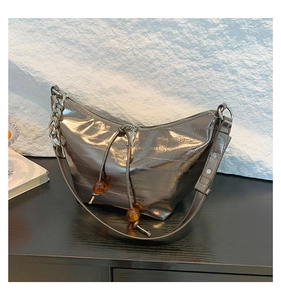 Detalle del bolso hobo plateado metalizado con cordón, cuentas ámbar y cadena