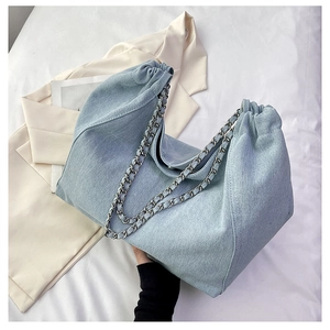 Detail shot of light blue denim bucket bag with metal chain strap and drawstring closure