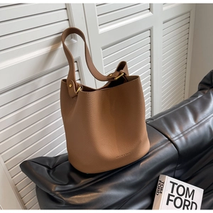Détail d'un sac seau en cuir marron à motif litchi avec des boucles en métal doré