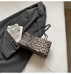 Détail du sac à main imprimé léopard avec bandoulière chaîne sur un tissu gris