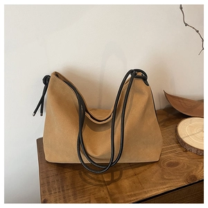 Gros plan du sac cabas en daim avec bandoulière en corde noire sur fond en bois