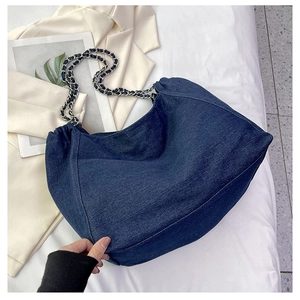 Detailed macro view of woven denim and metal chain shoulder strap on a navy tote bag