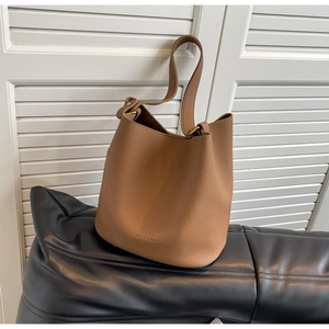 Vue macro du cuir grainé caramel et du logo de la marque sur le sac seau
