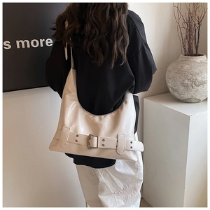 Detail of white patent leather hobo bag with vintage buckle on a model's shoulder