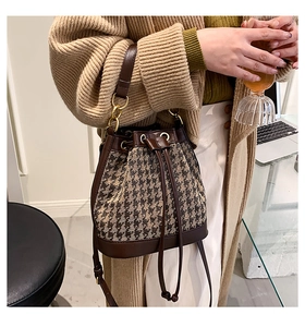 Detail of drawstring bucket bag with houndstooth pattern and leather trim