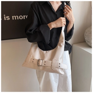Close-up of stylish beige shoulder bag with metallic buckle detail and long strap