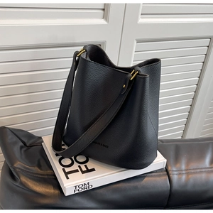 Détail d'un sac seau en cuir grainé noir avec finitions dorées et logo de la marque
