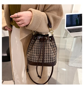 Detail view of houndstooth bucket bag with leather trim and gold ring handle