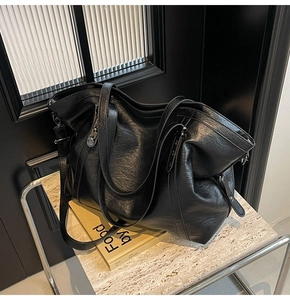Close-up of black tote bag showing premium litchi grain texture and metallic buckles