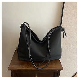 Détail du grand sac hobo noir avec des nœuds élégants sur la bandoulière pour un look chic