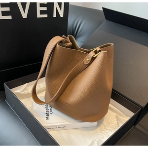 Détail du sac seau marron en cuir grainé avec boucles dorées et emballage cadeau de luxe
