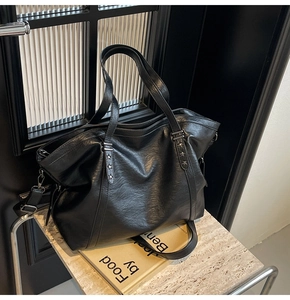Detail of black tote bag with silver star rivets and textured leather on a marble surface