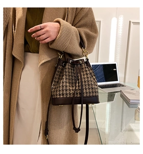 Close-up of houndstooth bucket bag with leather trim and drawstring detail