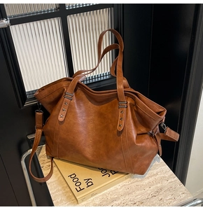 Detail of caramel brown tote bag showing pebble leather texture and metal star rivets