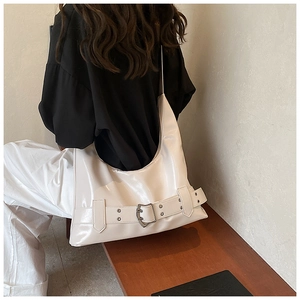 Detailed side view of white glossy hobo bag with decorative buckles for daily outfit