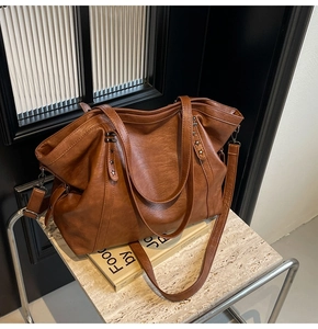 Close-up of brown PU leather tote bag with metal star studs and removable long shoulder strap