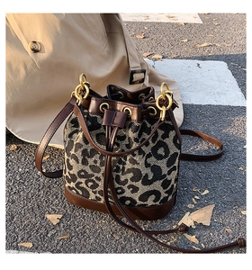 Detail of retro leopard print bucket bag with drawstring closure and golden hardware