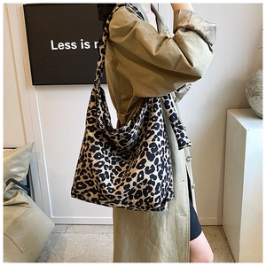 Detailed side view of leopard print canvas tote bag carried by a model in casual coat