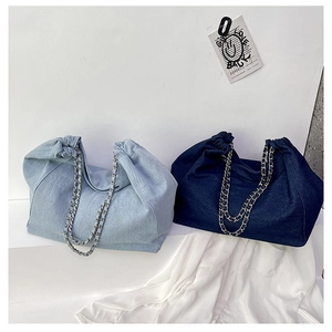 Detail of denim tote bags with drawstring closure and metal chain shoulder straps