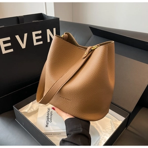 Vue détaillée du sac seau en cuir marron avec boucle dorée et coffret cadeau de luxe