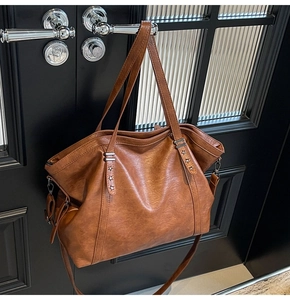 Close-up of caramel brown tote bag featuring silver star rivets and premium lychee texture