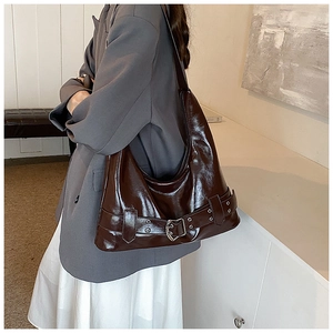 Detail of dark brown glossy shoulder bag with silver buckle and retro belt design