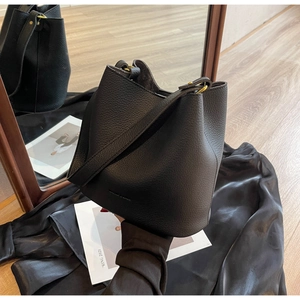 Détail du sac seau noir en cuir grainé avec finitions dorées et bandoulière ajustable