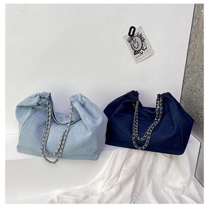 Detail of light and dark denim tote bags with metal chain straps on minimalist white steps