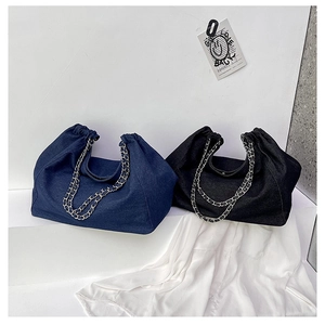 Detail view of denim tote bags with pleated openings and silver chain shoulder straps