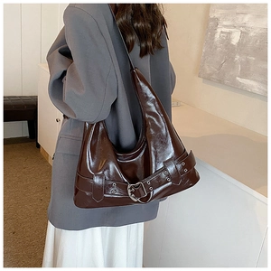 Detail of deep brown glossy leather shoulder bag featuring a silver heart metal buckle