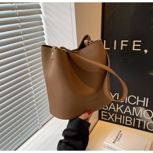 Détail du sac seau en cuir marron à motif litchi avec clous dorés et logo de marque