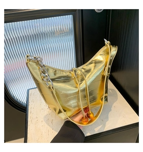 Detalle de bolso Hobo dorado en forma de media luna con acabado metálico y cadena plata