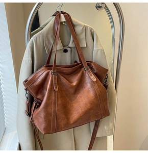 Detail of brown tote bag with star rivets and adjustable strap over a beige trench coat