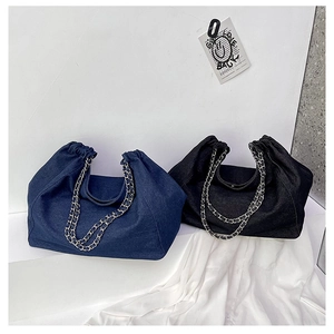 Detail of denim tote bags featuring drawstring closure and metallic chain straps