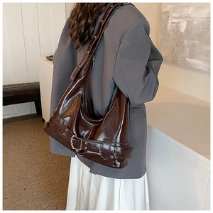 Detail of dark brown vintage motorcycle style underarm bag with decorative metal buckle