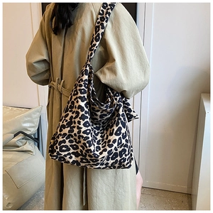 Detailed back view of a woman wearing a large leopard print canvas tote bag over a trench coat