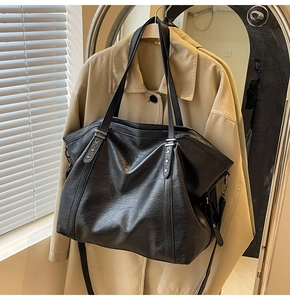 Detail of black tote bag showing silver star rivets and premium leather texture on trench coat