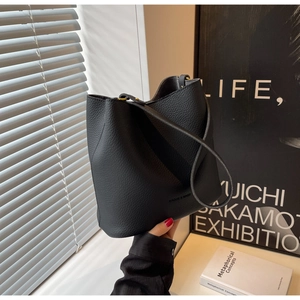 Détail du sac seau noir en cuir grainé avec ferrures dorées et bandoulière fine