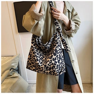 Detail of trendy leopard print tote bag with knotted shoulder strap worn by a model