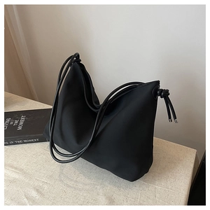 Détail d'un sac cabas noir minimaliste avec anses rondes et nœud décoratif latéral