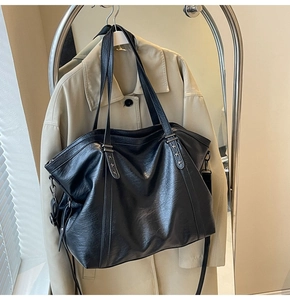 Detail of black leather tote bag featuring star rivets and dual-style shoulder straps