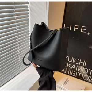 Détail du sac seau en cuir grainé noir avec finitions dorées et logo embossé