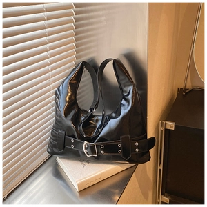 Detail of black glossy Hobo bag featuring decorative silver buckles and metal eyelets