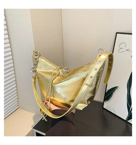 Detalle de bolso hobo dorado metalizado con acolchado horizontal y cadena plateada