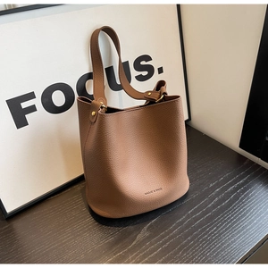 Détail d'un sac seau en cuir marron motif litchi avec finitions dorées et logo