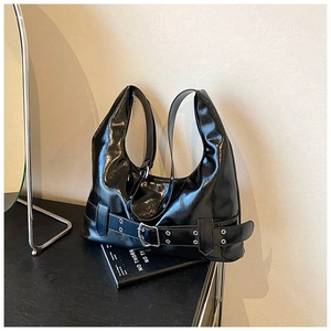 Detail view of black patent leather hobo bag with silver buckle and mirror-like finish