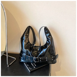 Detail of glossy black hobo bag featuring silver eyelets and buckle strap decoration