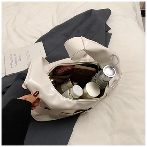 Spacious interior of white PU leather shoulder bag showing everyday items and knotted handle