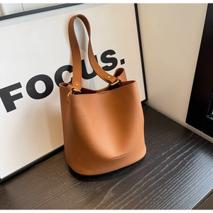 Détail d'un sac seau marron caramel avec texture litchi et finitions en métal doré