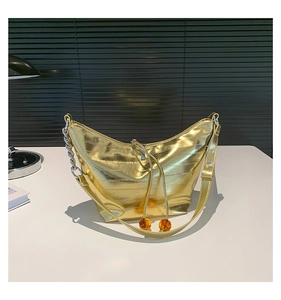 Detalle del bolso dumpling dorado con textura plisada, cadena plateada y cuentas de ámbar
